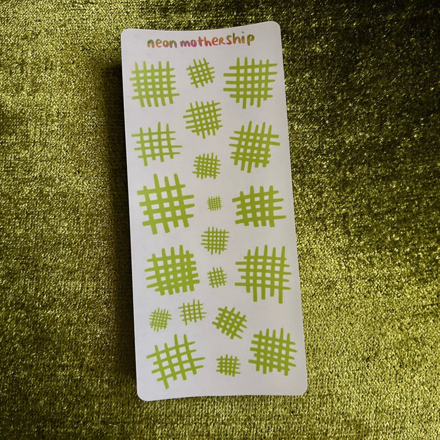 Sheet of green geometric stickers on a textured green surface