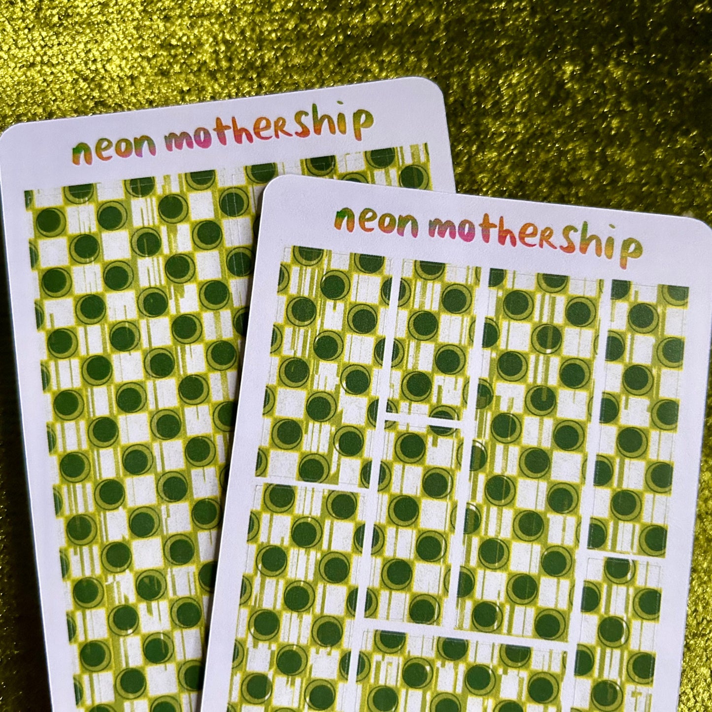 Two sticker sheets with green and white pattern on a gold glitter background