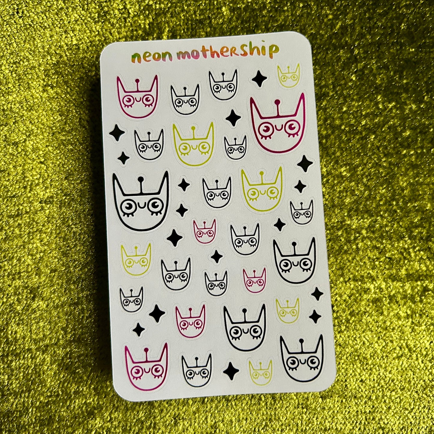 Sticker sheet with cat-themed designs on a green textured background