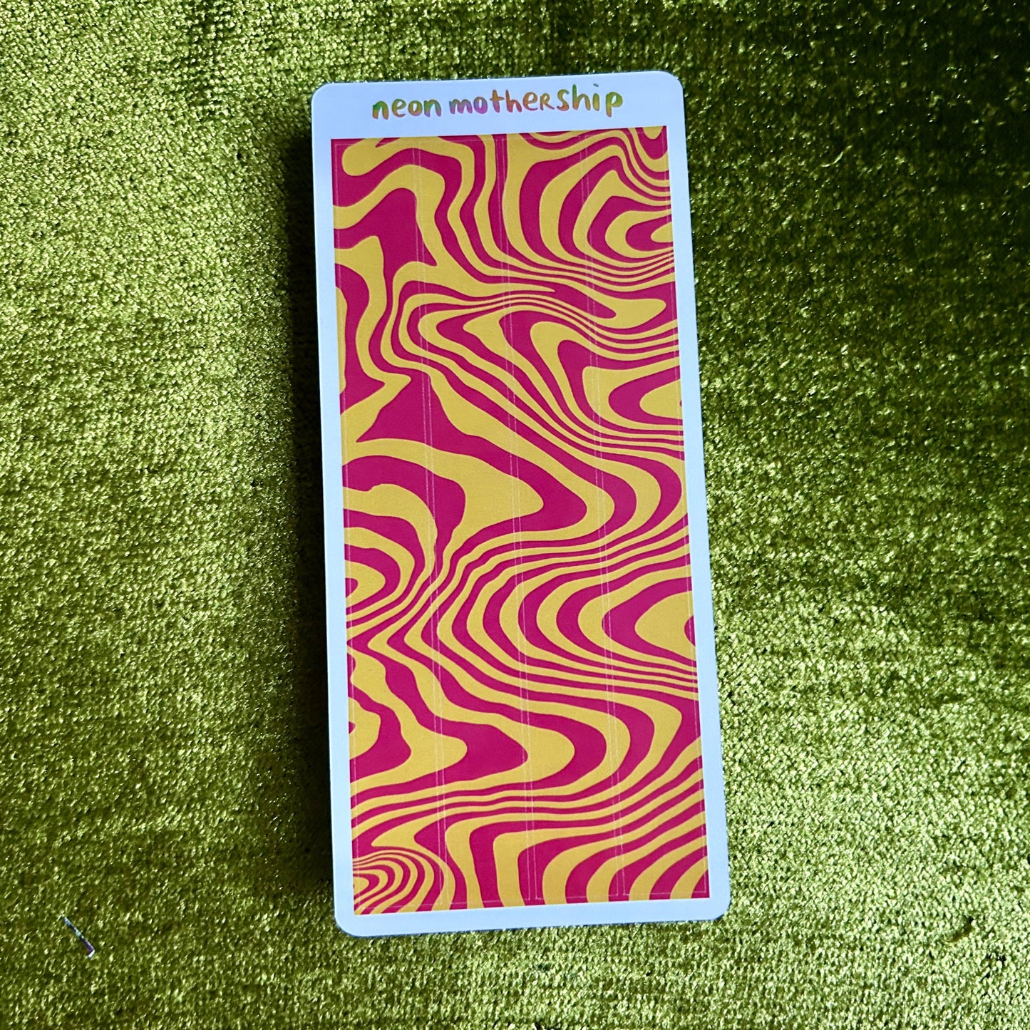 Rectangular sticker sheet with wavy pink and yellow pattern on a green textured background