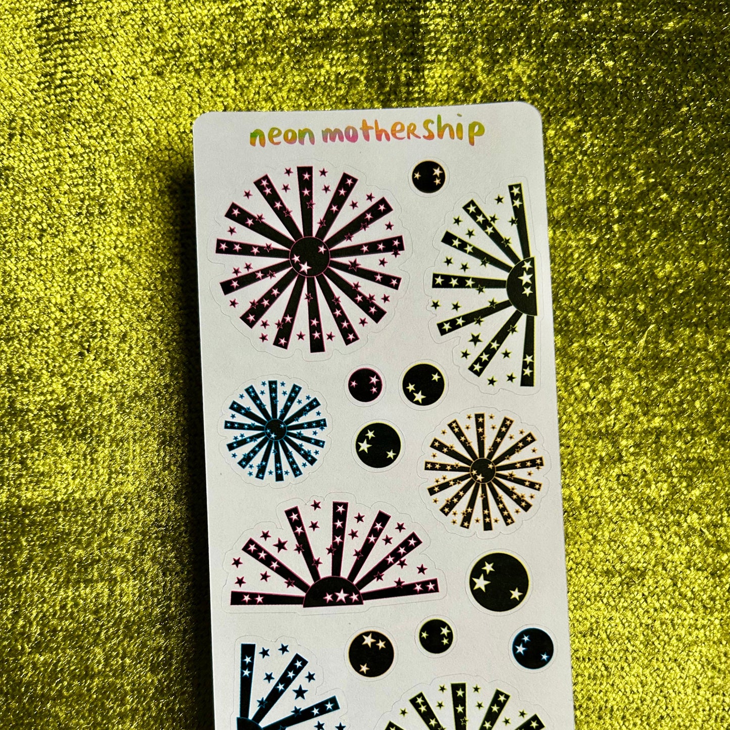 Sheet of decorative stickers with starburst designs on a green textured background