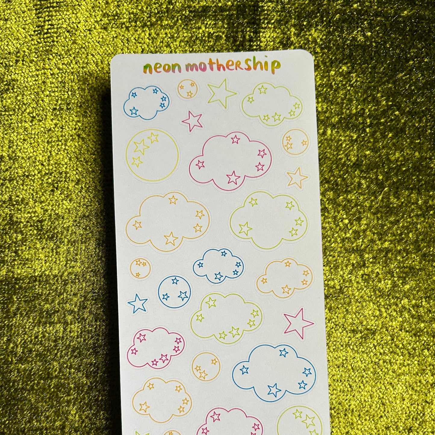Sheet of colorful cloud and star stickers on a green textured background
