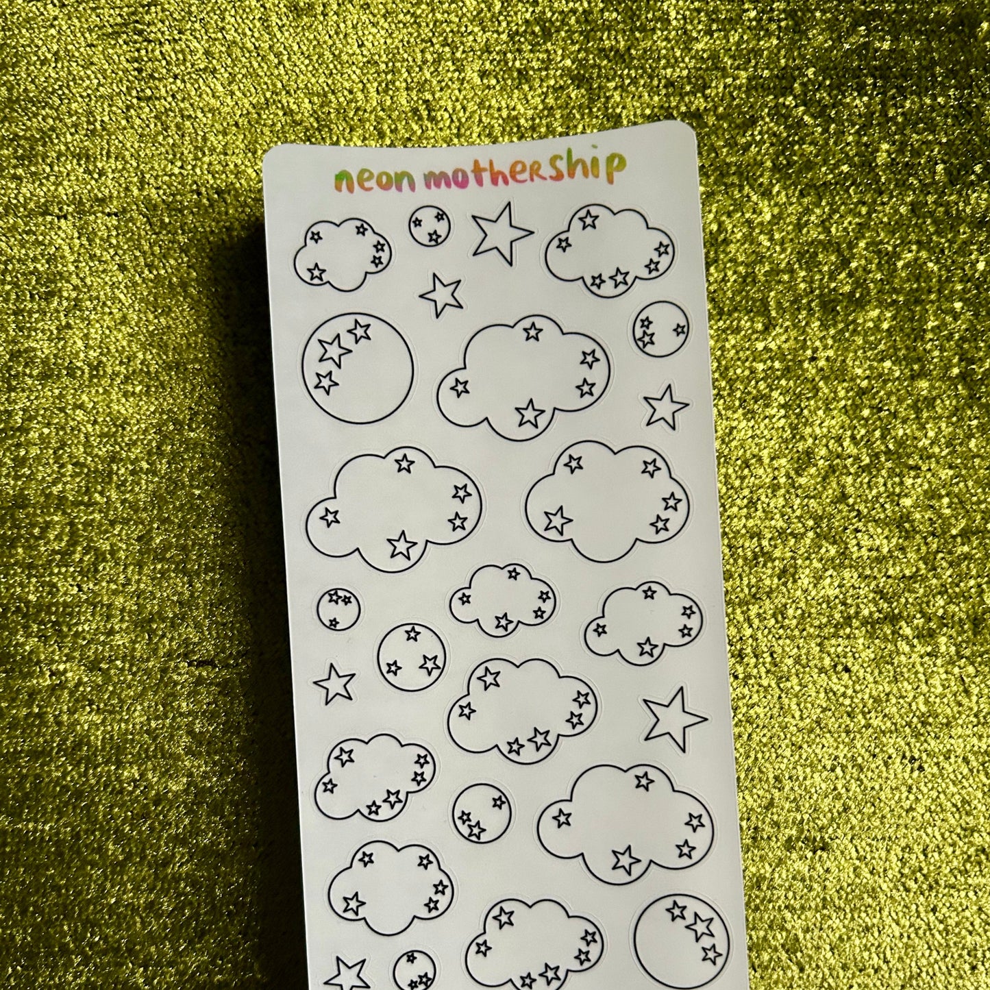 Sheet of cloud and star stickers on a green textured surface