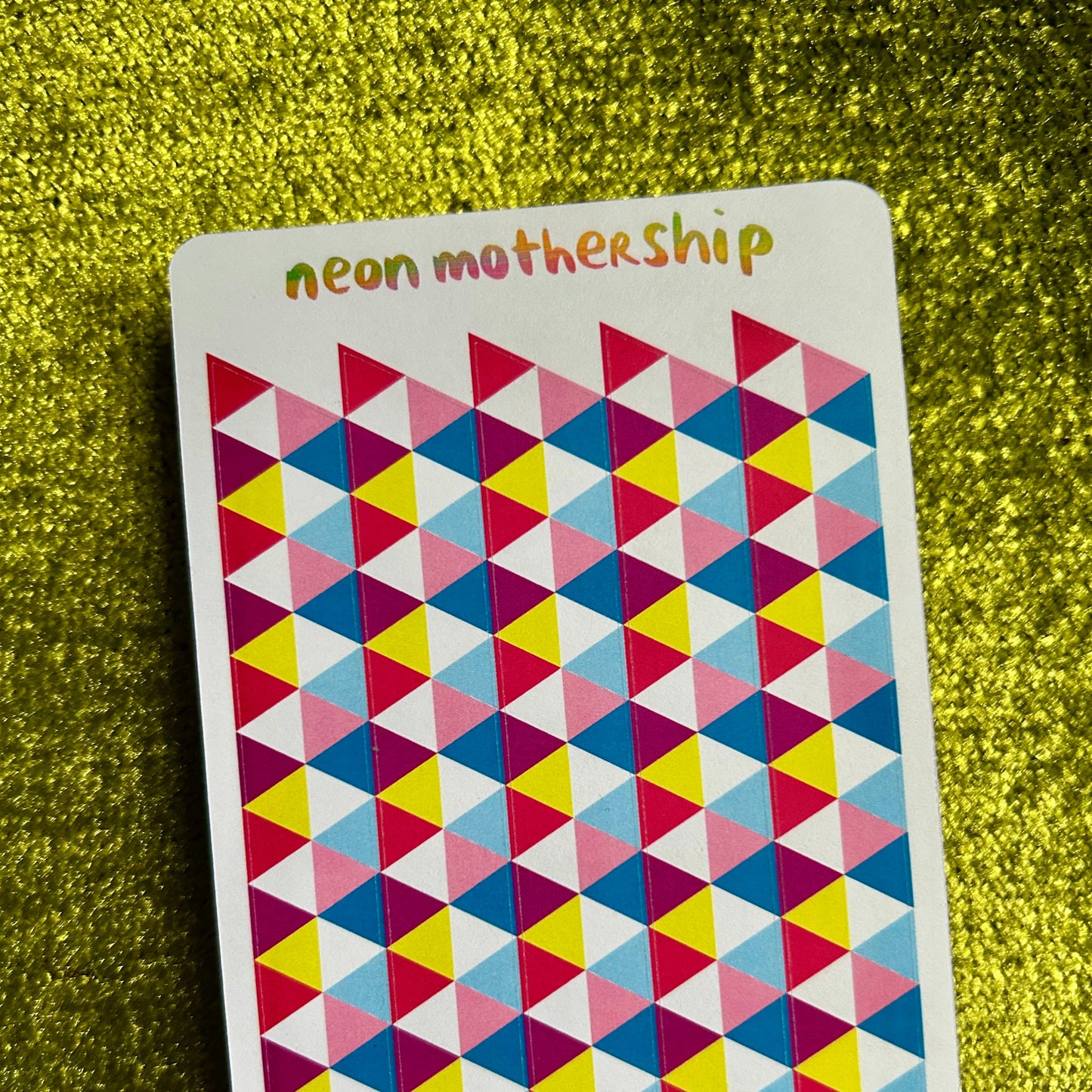 Colorful geometric patterned sticker sheet with 'neon mothership' text on a green textured background