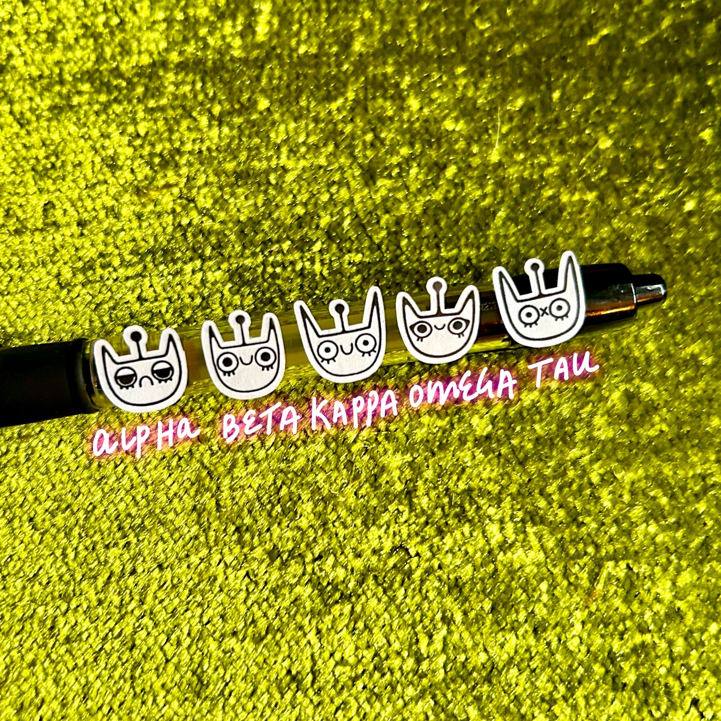 Pen with decorative spacecat stickers on a green textured background