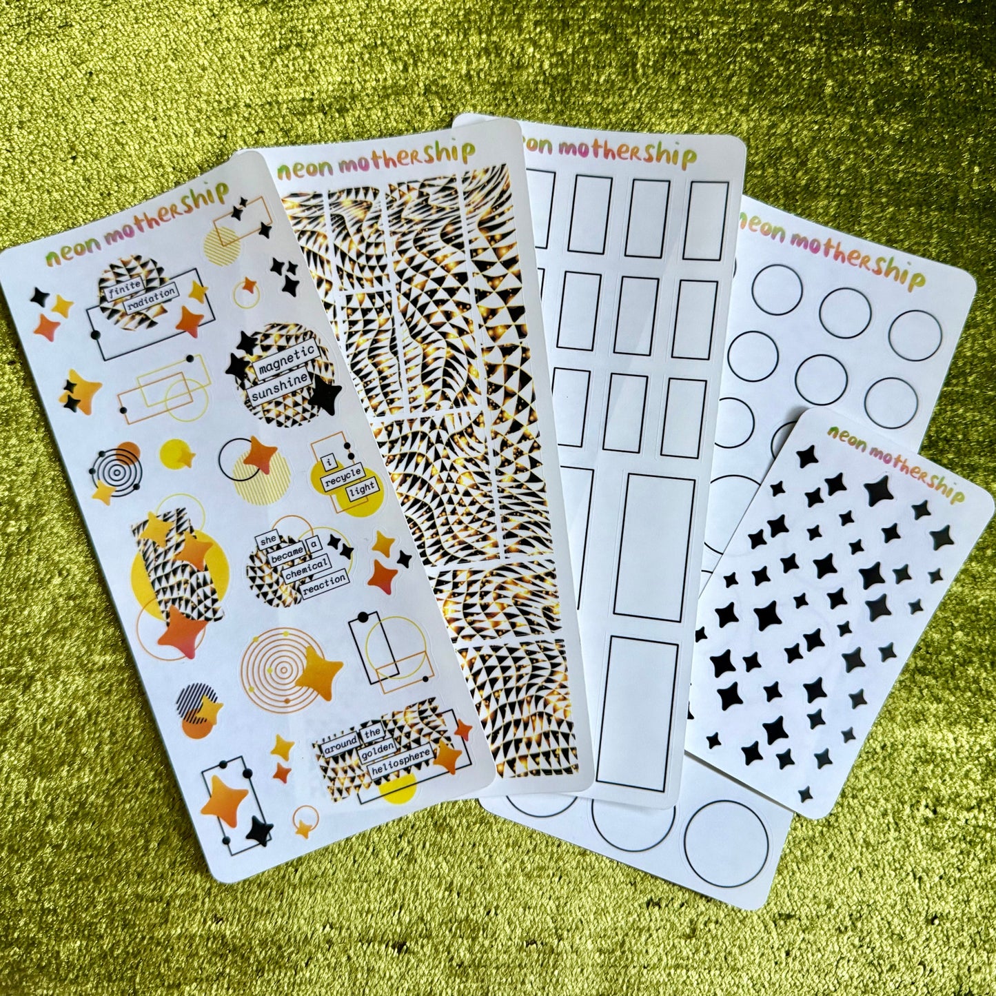 five sheets of decorative stickers on a green textured surface