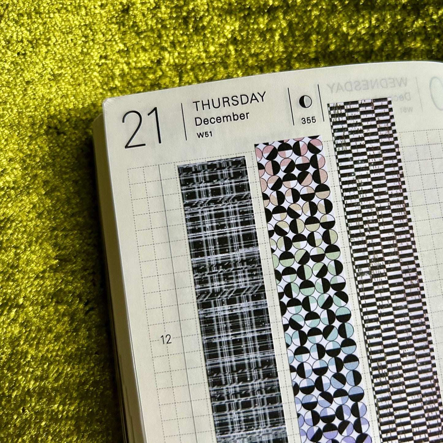 Open planner with decorative washi tape strips on a green textured surface