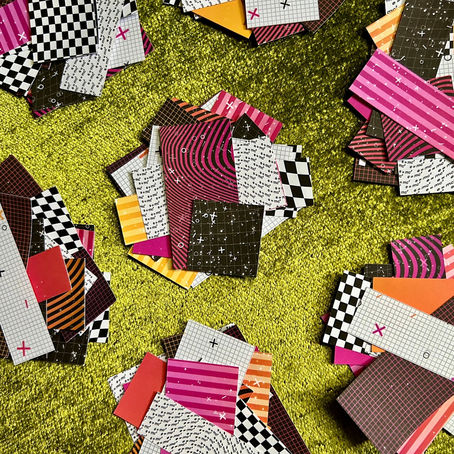 Colorful patterned paper pieces scattered on a green surface