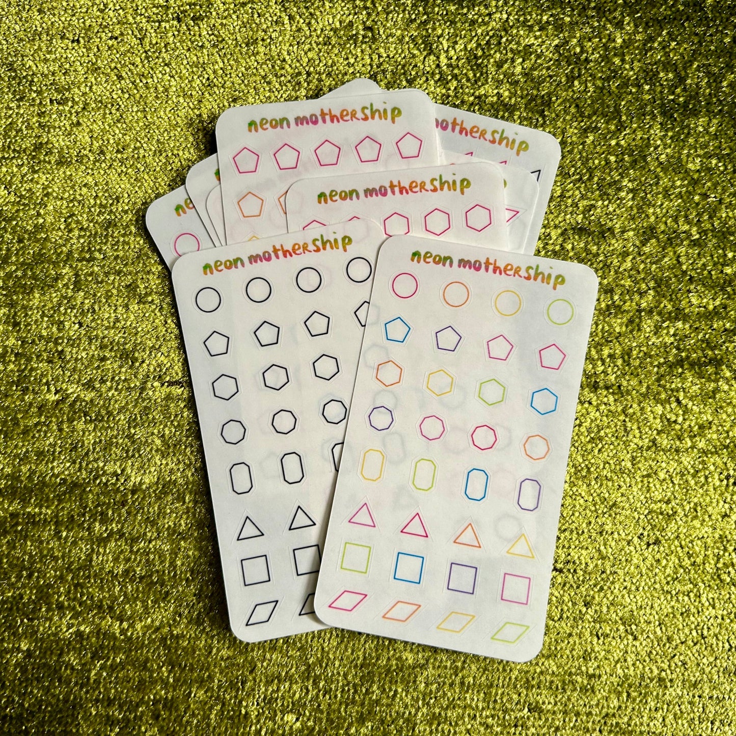 assorted sticker sheets with geometric pattern designs on a green textured surface