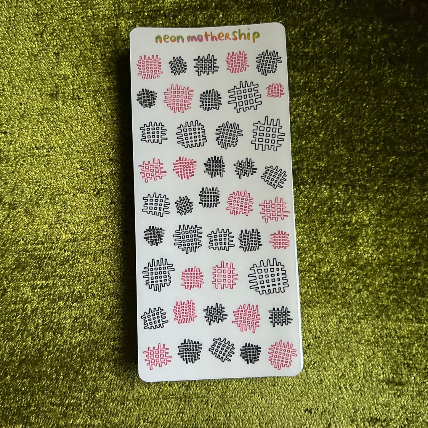 Sheet of stickers with geometric patterns on a green textured surface