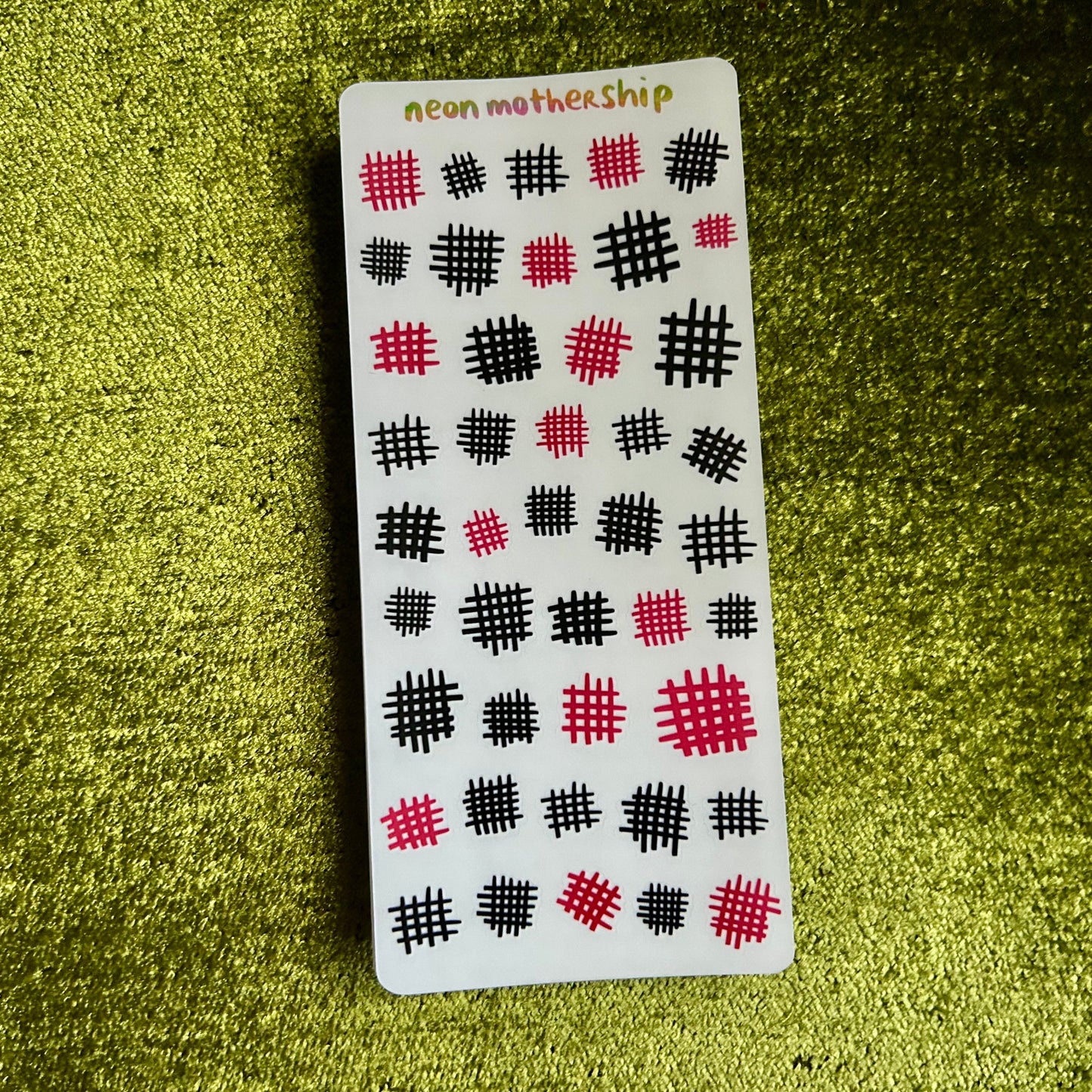 sticker sheet card with black and pink pattern on a green textured surface