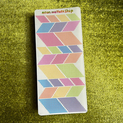 Colorful geometric patterned stickers on a green textured surface