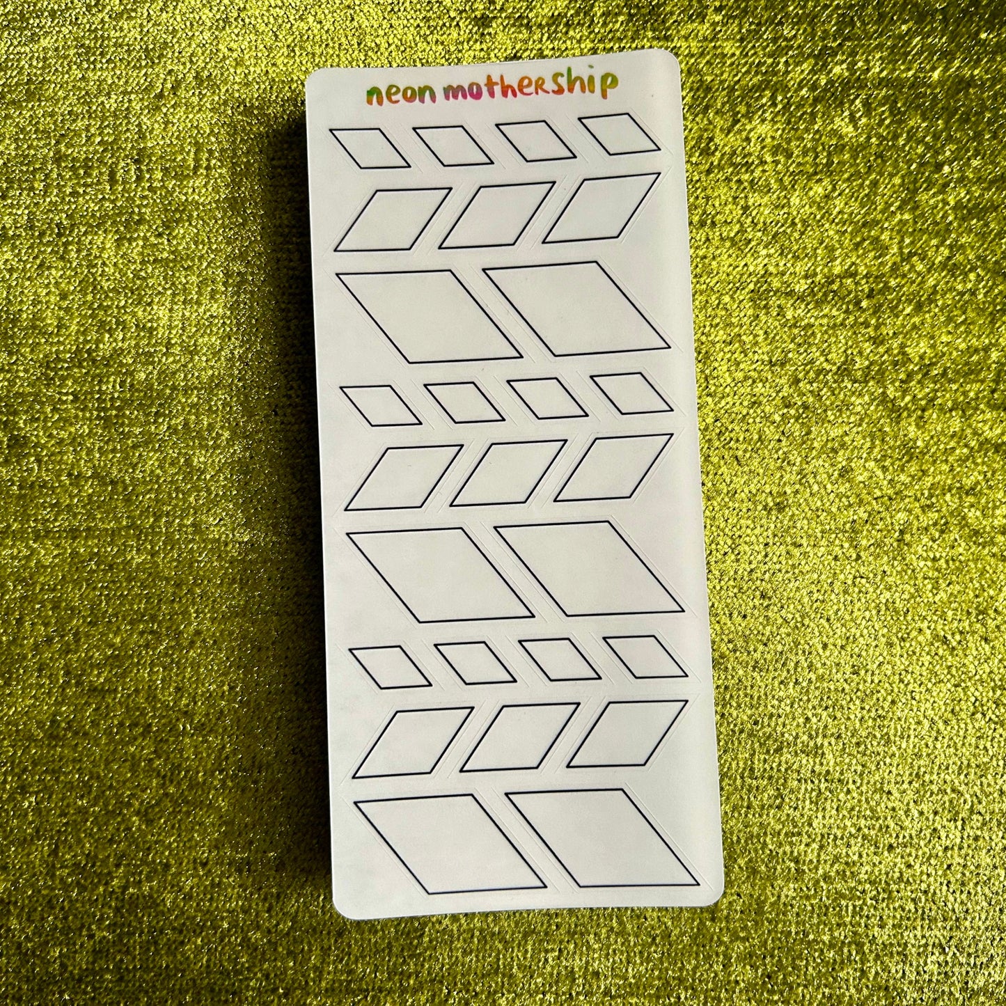 Sheet of geometric stickers with 'neon mother ship' branding on a green textured background