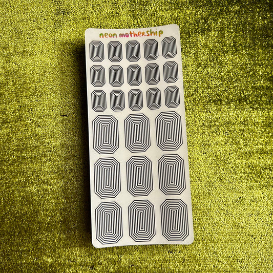 Sheet of black and white oval stickers on a textured green surface