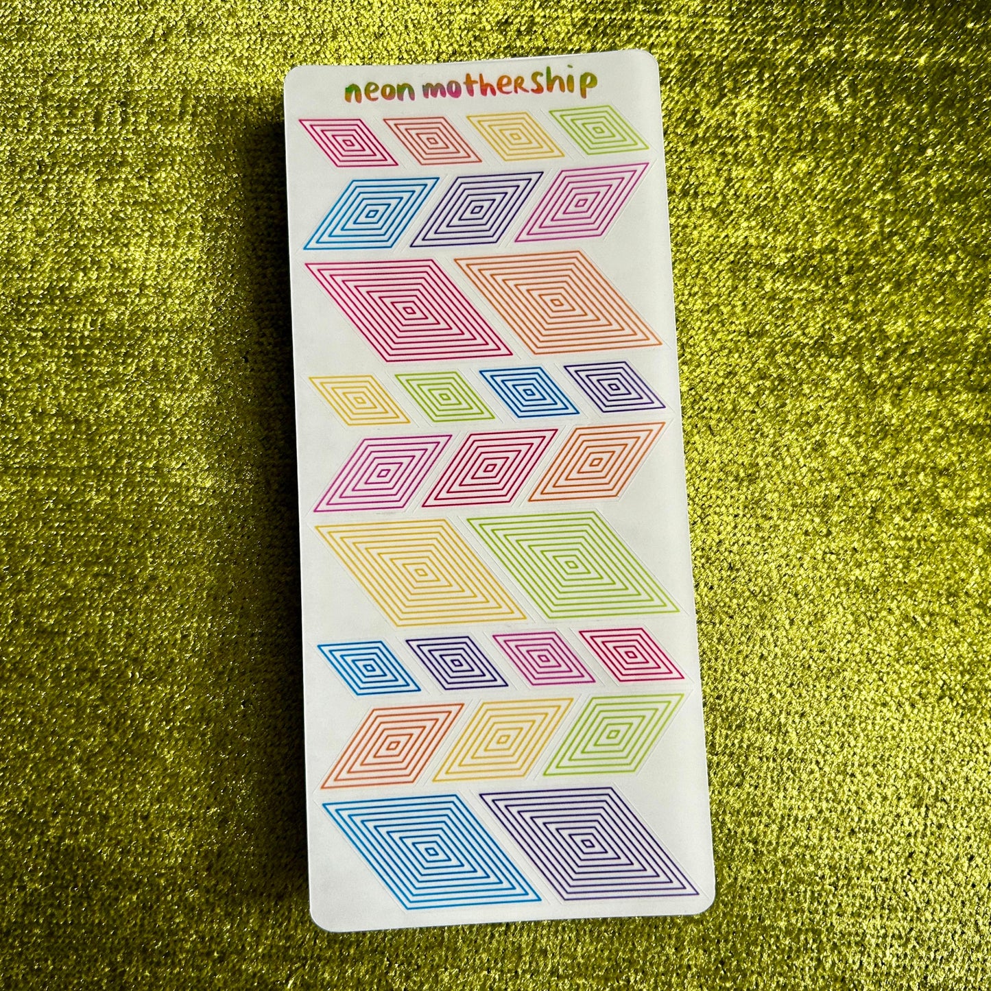 Pack of colorful geometric stickers on a green textured surface