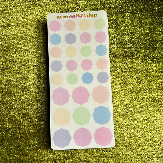 Sheet of pastel polka dot stickers on a green textured background