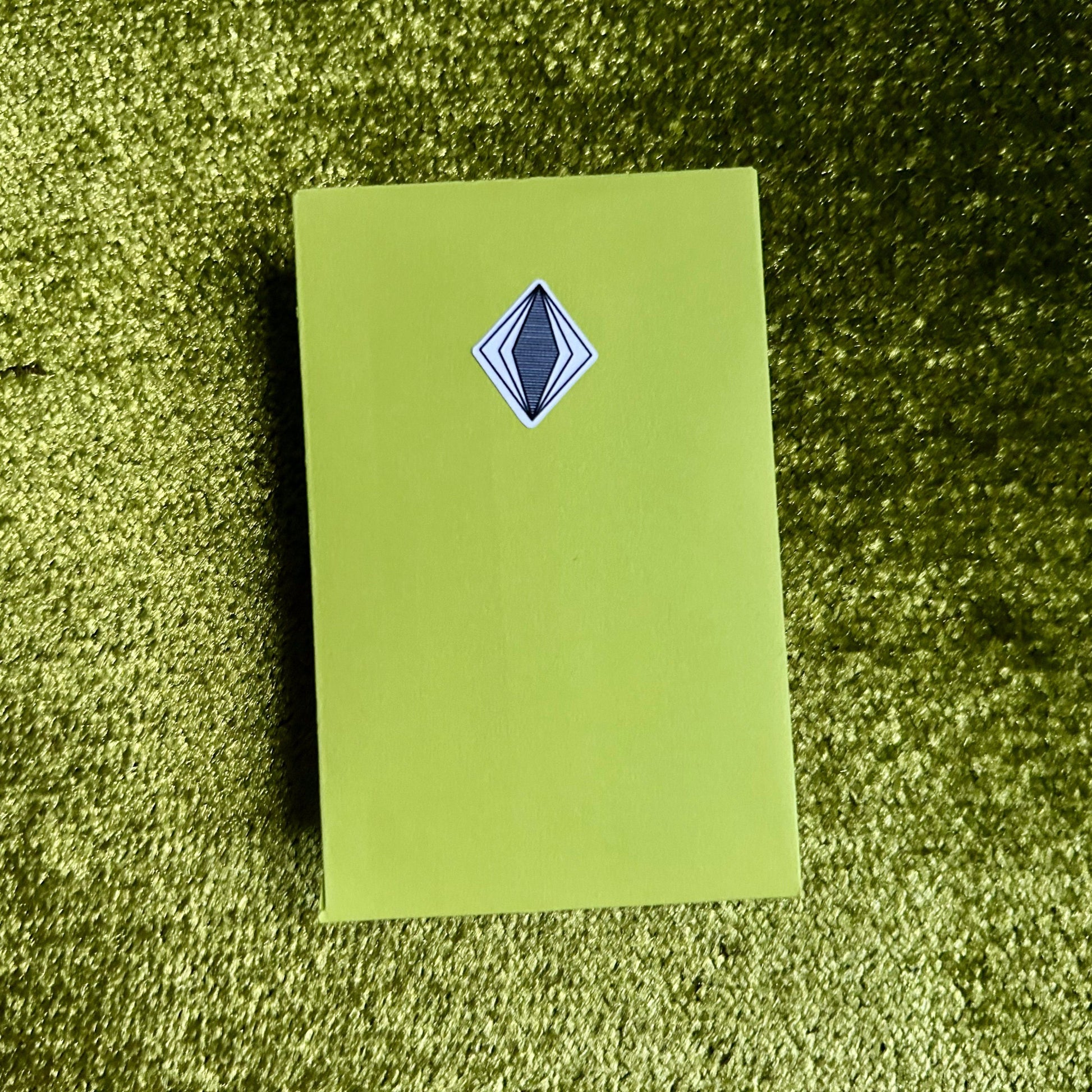 Green envelope with a blue diamond-shaped logo on a green textured surface