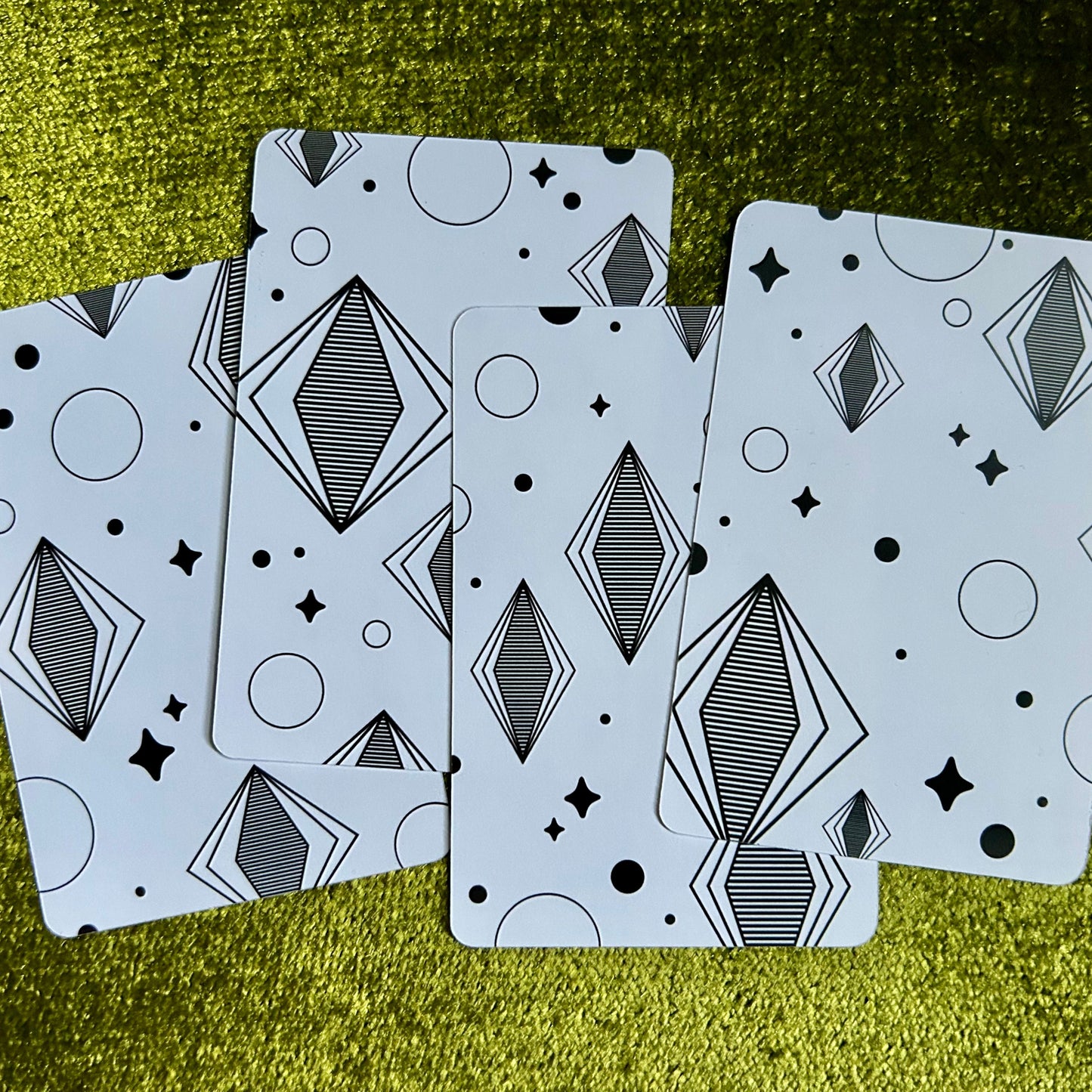 Four art prints with geometric patterns on a green textured surface