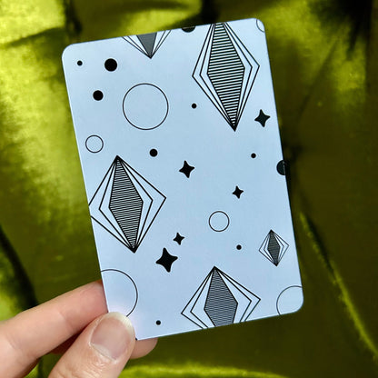 Card with geometric pattern held by a hand against a green fabric background