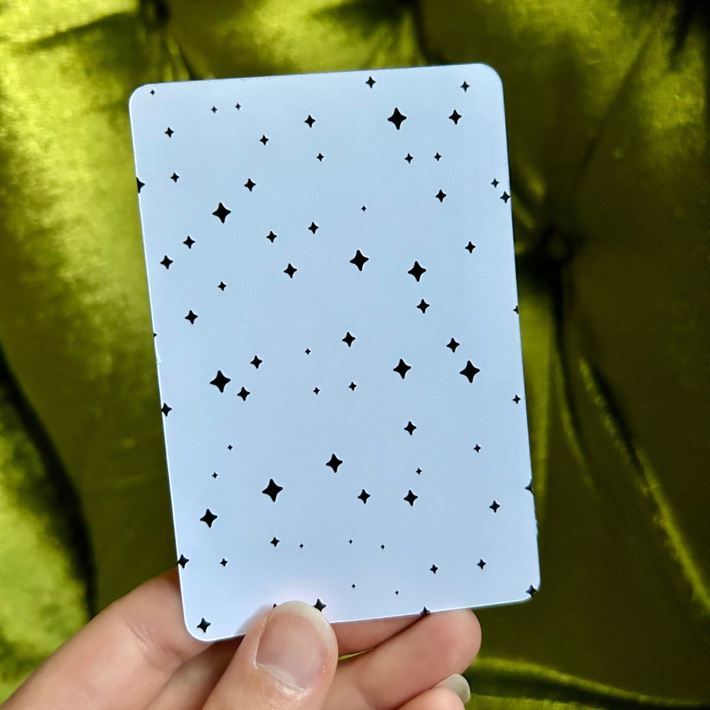 art print with star sparkles pattern held by a hand against a green fabric background