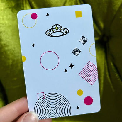 Card with geometric patterns held by a hand against a green fabric background