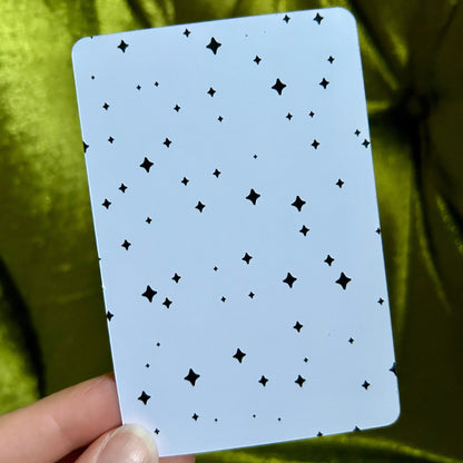 Card with star pattern held by a hand against a green fabric background