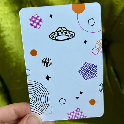 Card with geometric patterns and a logo held by a hand against a green fabric background