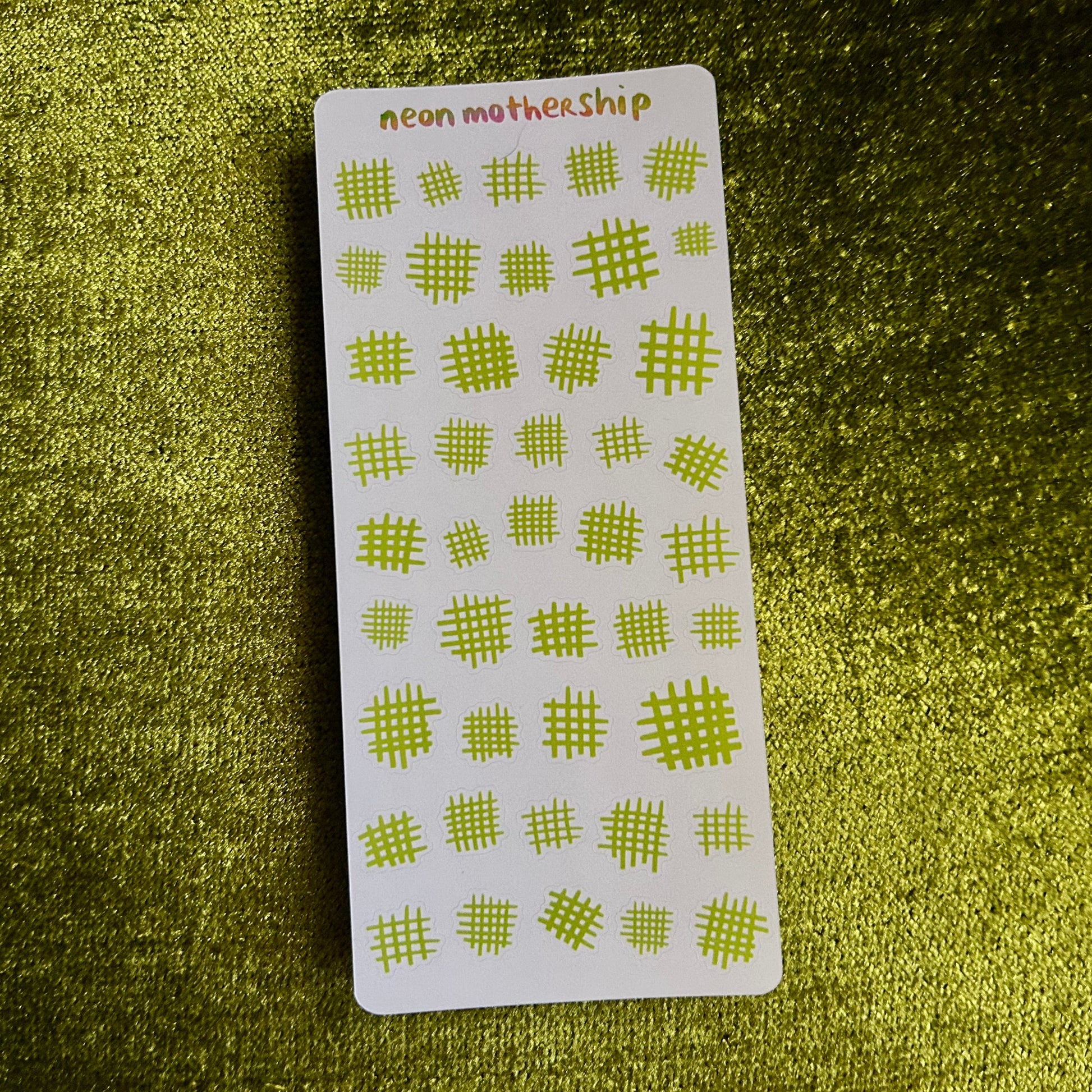 Sheet of green geometric stickers on a textured green surface