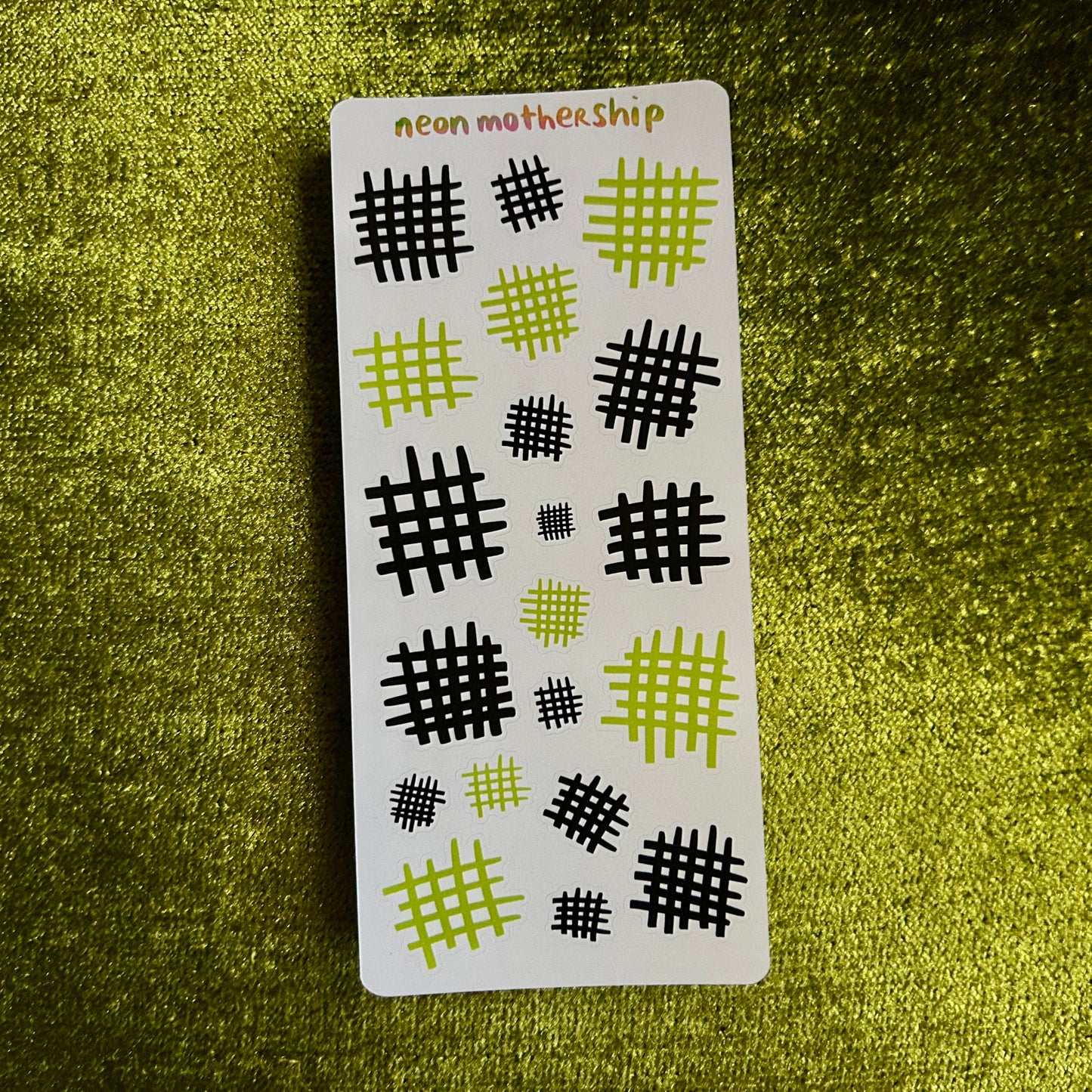 Card with black and green patterned designs on a textured green surface