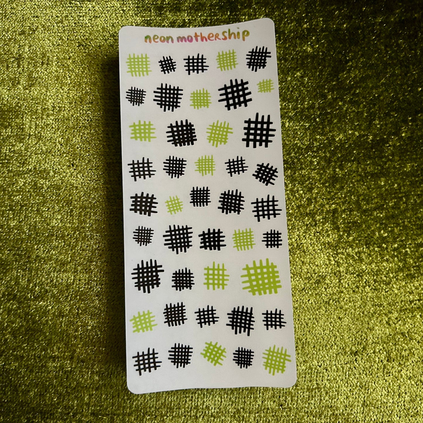Sheet of black and green patterned stickers on a textured green surface
