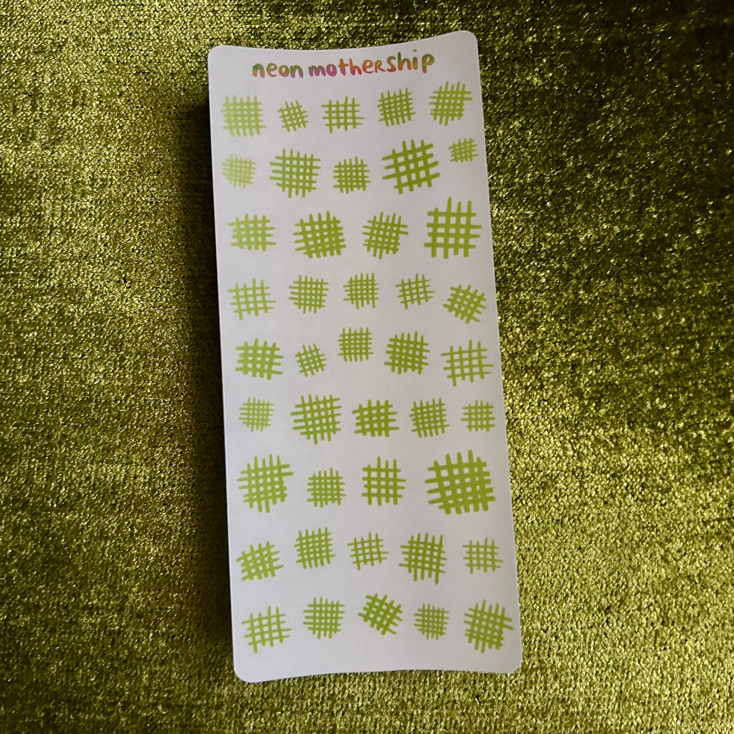 Sheet of green checkered stickers on a textured green surface
