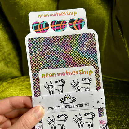 Hand holding a deck of cards with 'neon mothership' branding and designs.