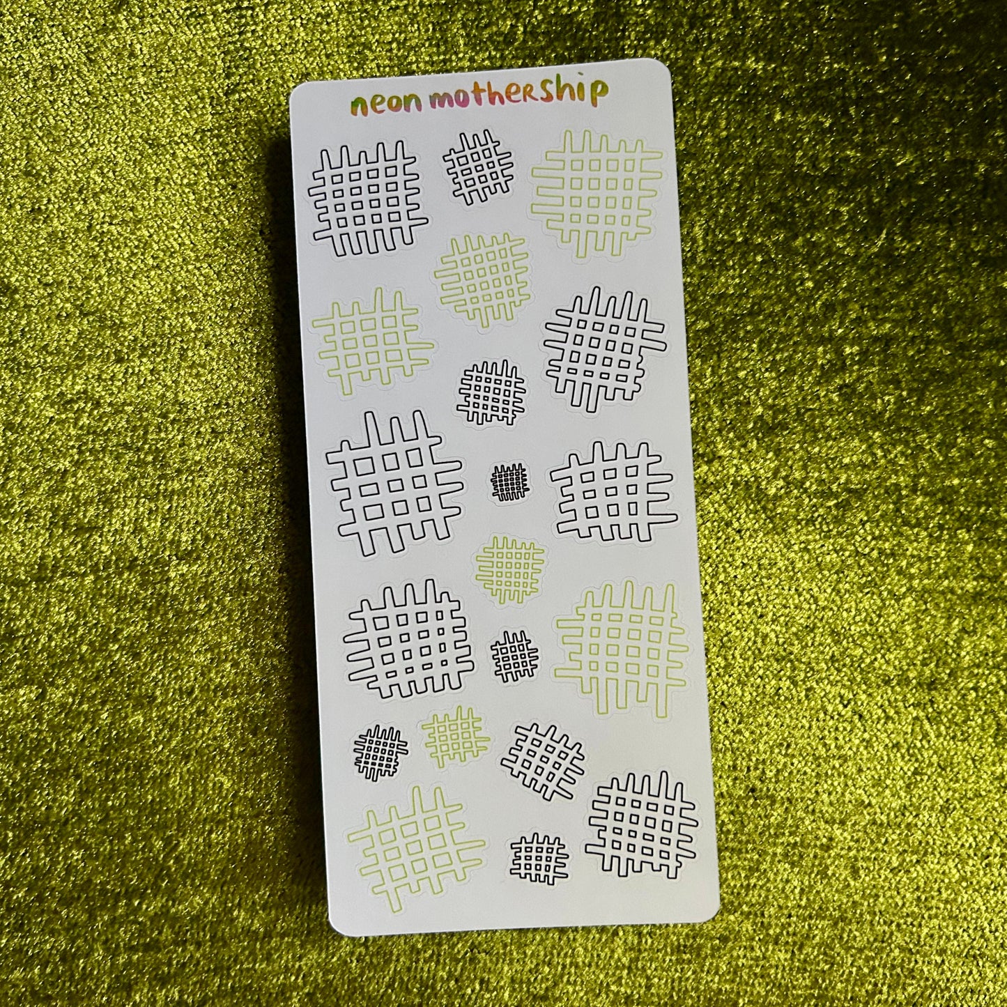 Sheet of patterned stickers with 'neon mother ship' branding on a green textured background