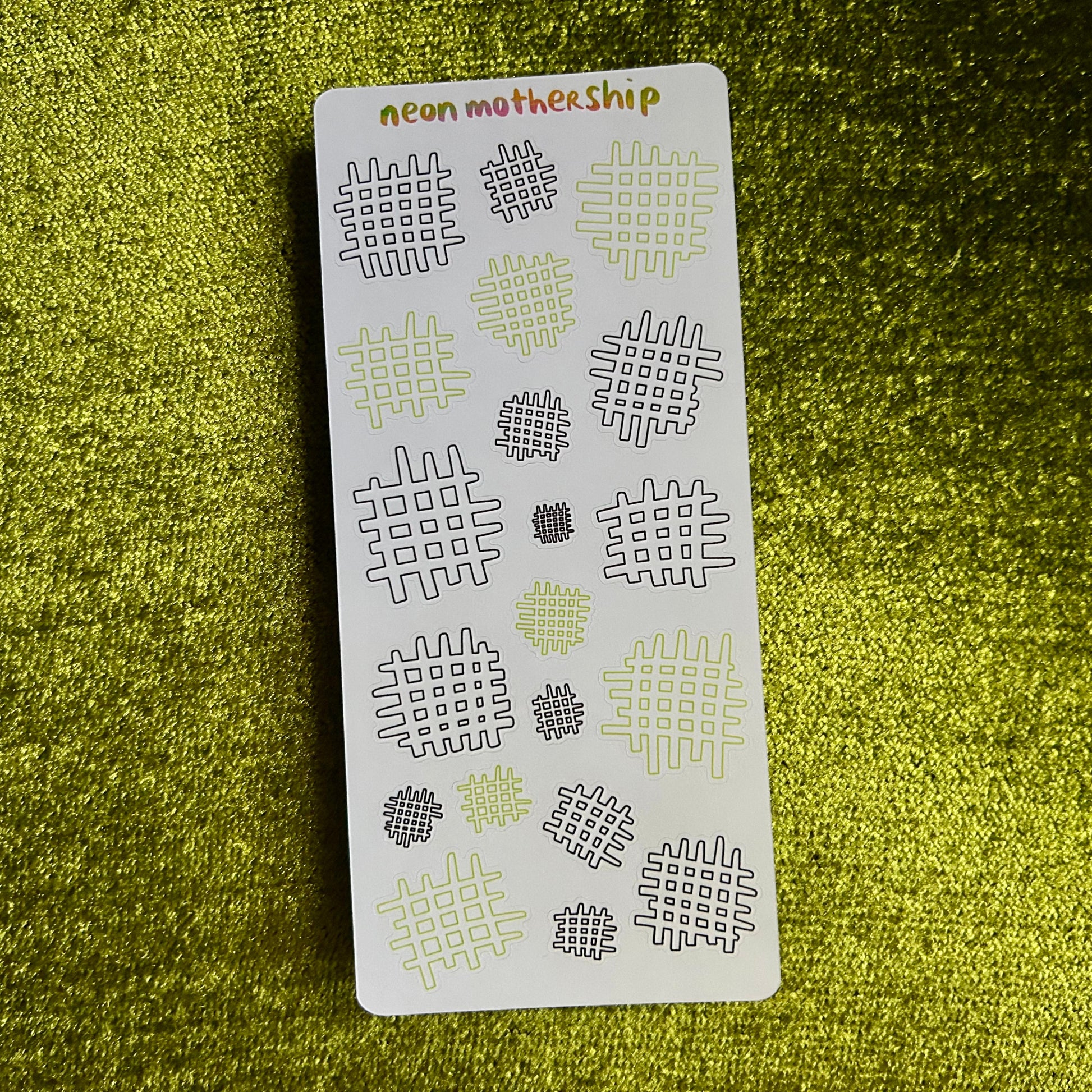 Sheet of patterned stickers with 'neon mother ship' branding on a green textured background