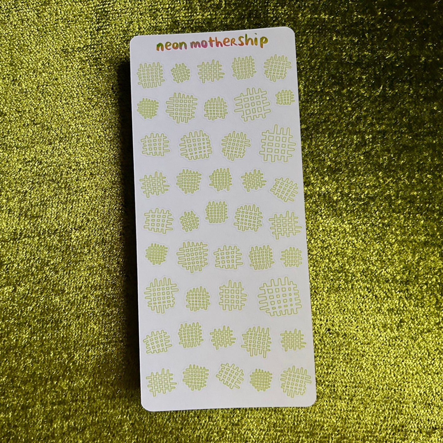 Sheet of green waffle-patterned stickers on a green textured surface