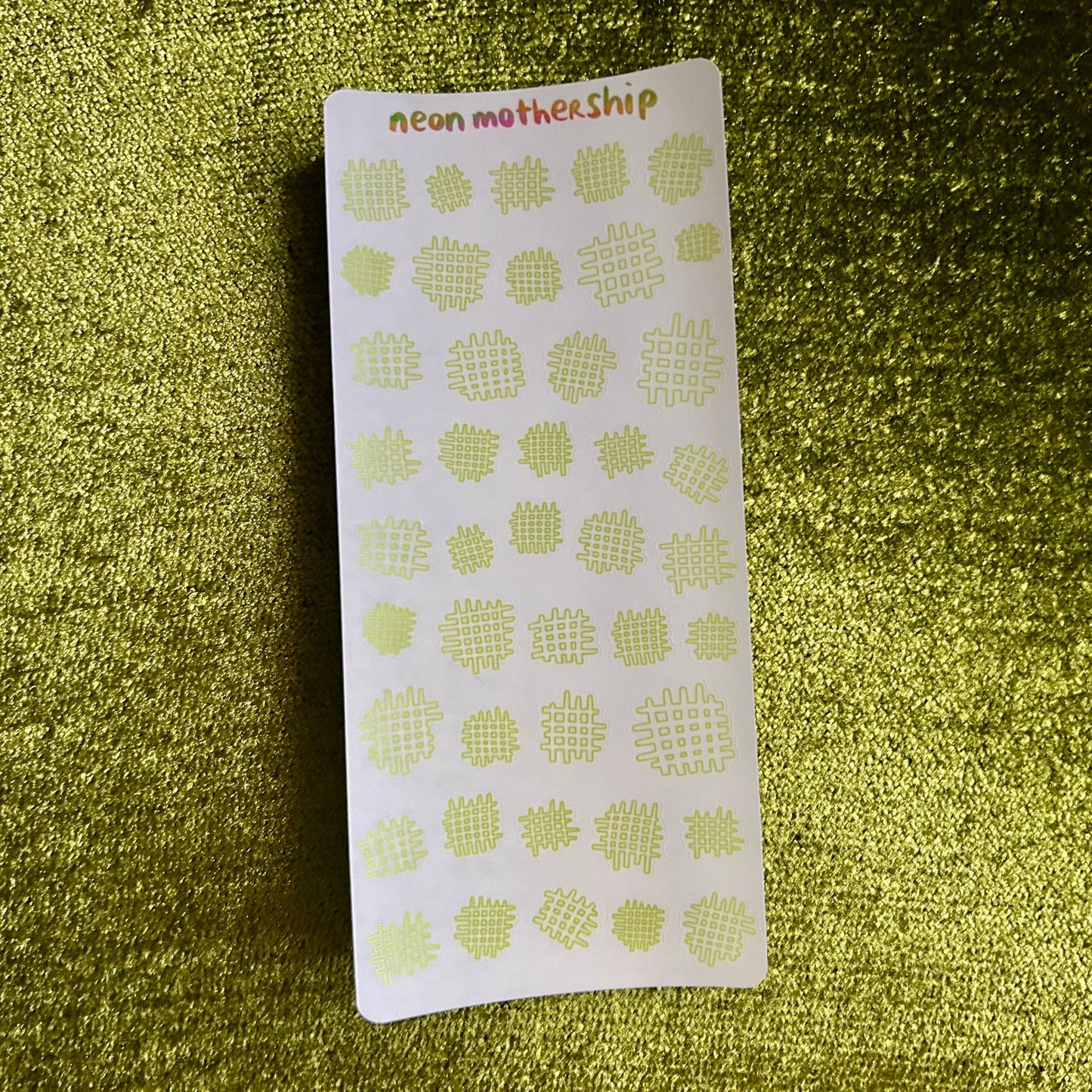 Sheet of green waffle-patterned stickers on a glittery green background