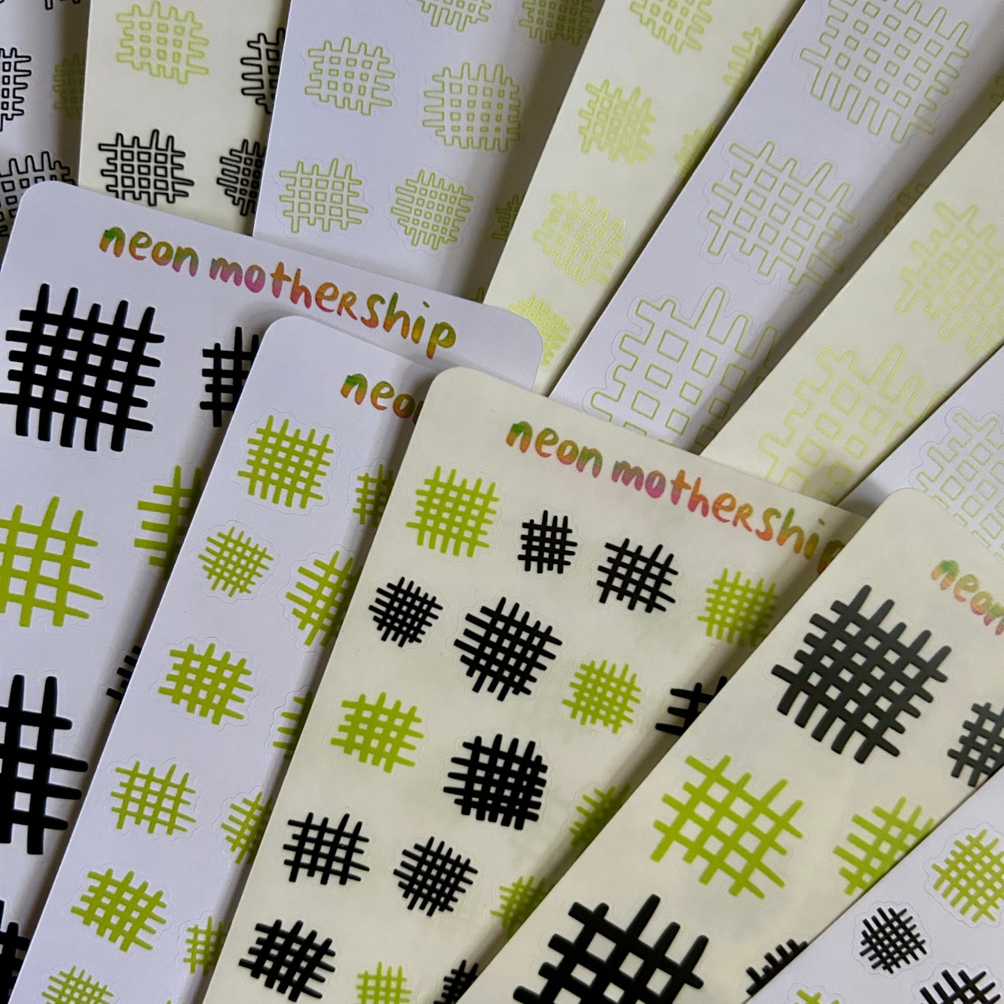 Stack of sticker sheets with geometric patterns and 'neon mothership' branding.