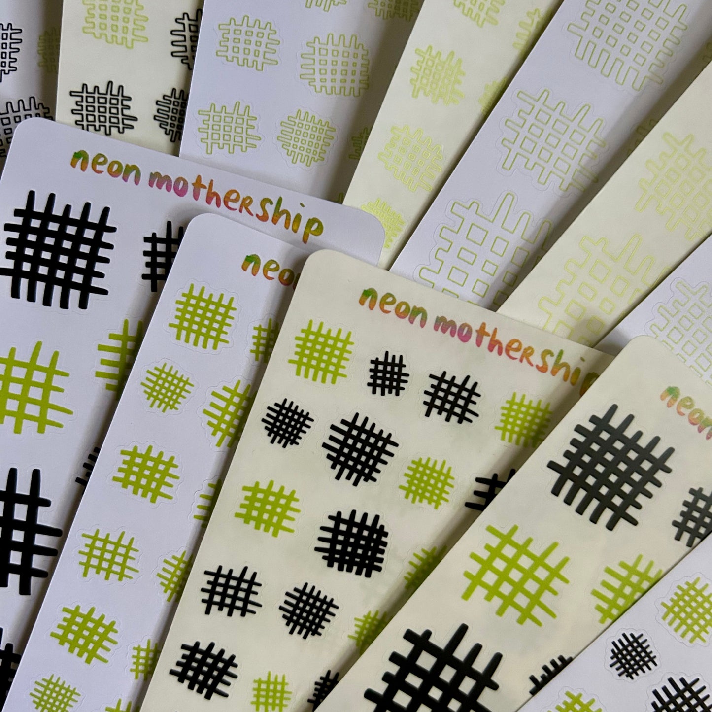 Stack of sticker sheets with geometric patterns and 'neon mothership' branding.