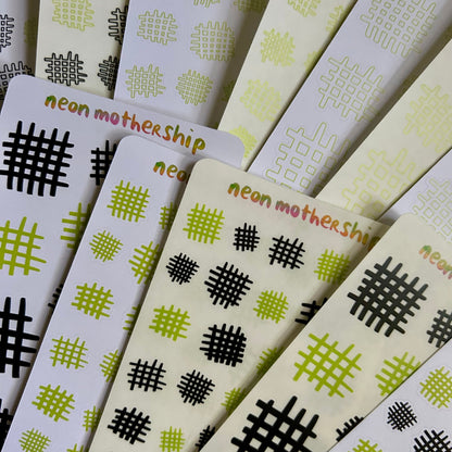 Stack of sticker sheets with geometric patterns and 'neon mothership' branding.