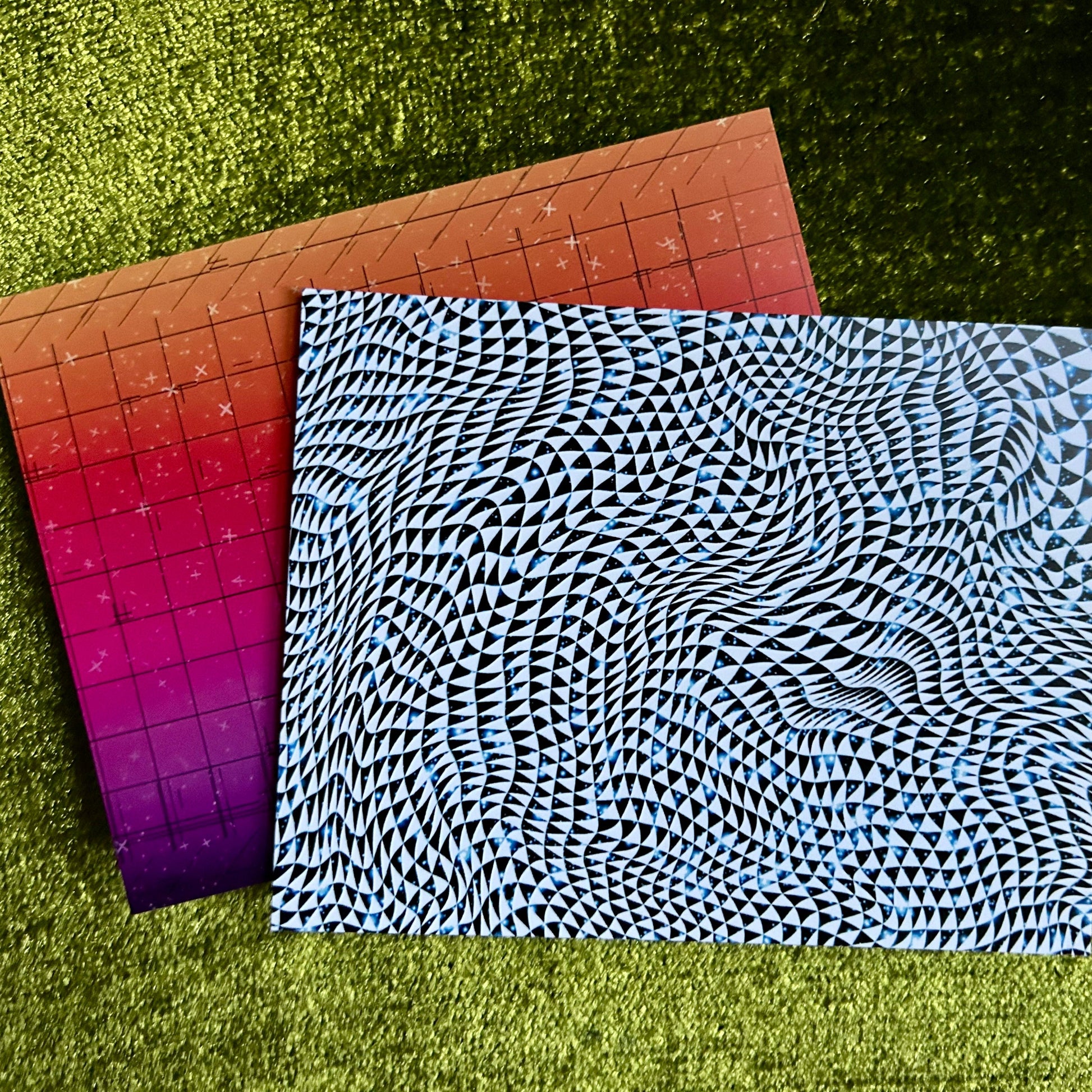Two neon patterned postcards on a green grass background