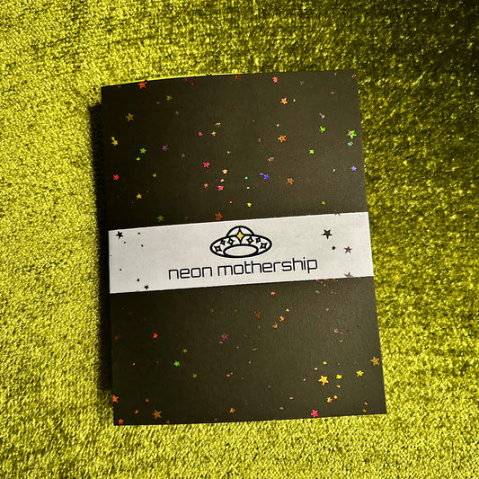 Black paper with colorful holographic star patterns on a green textured surface