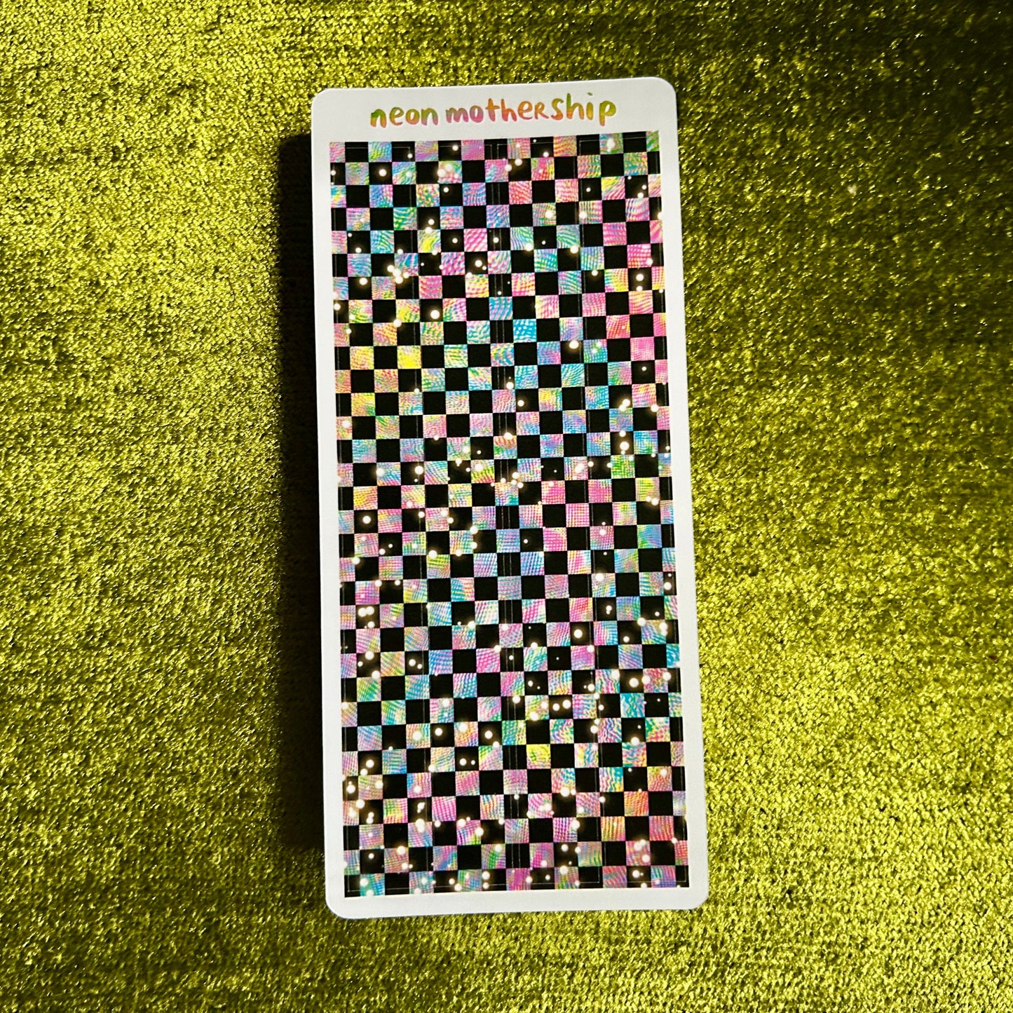 Checkered patterned sticker sheet with 'neon mothership' text on a green textured background