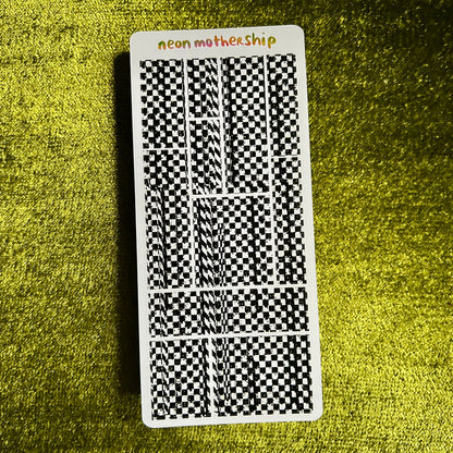 Sticker sheet with black and white checkered pattern on a green textured surface