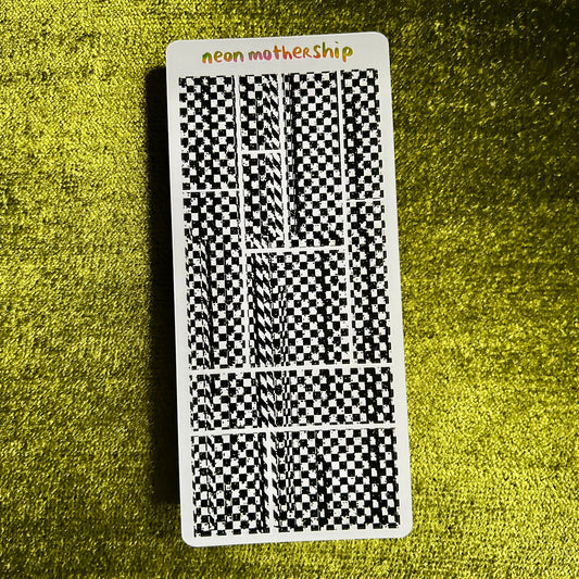 Sticker sheet with black and white checkered pattern on a green textured surface