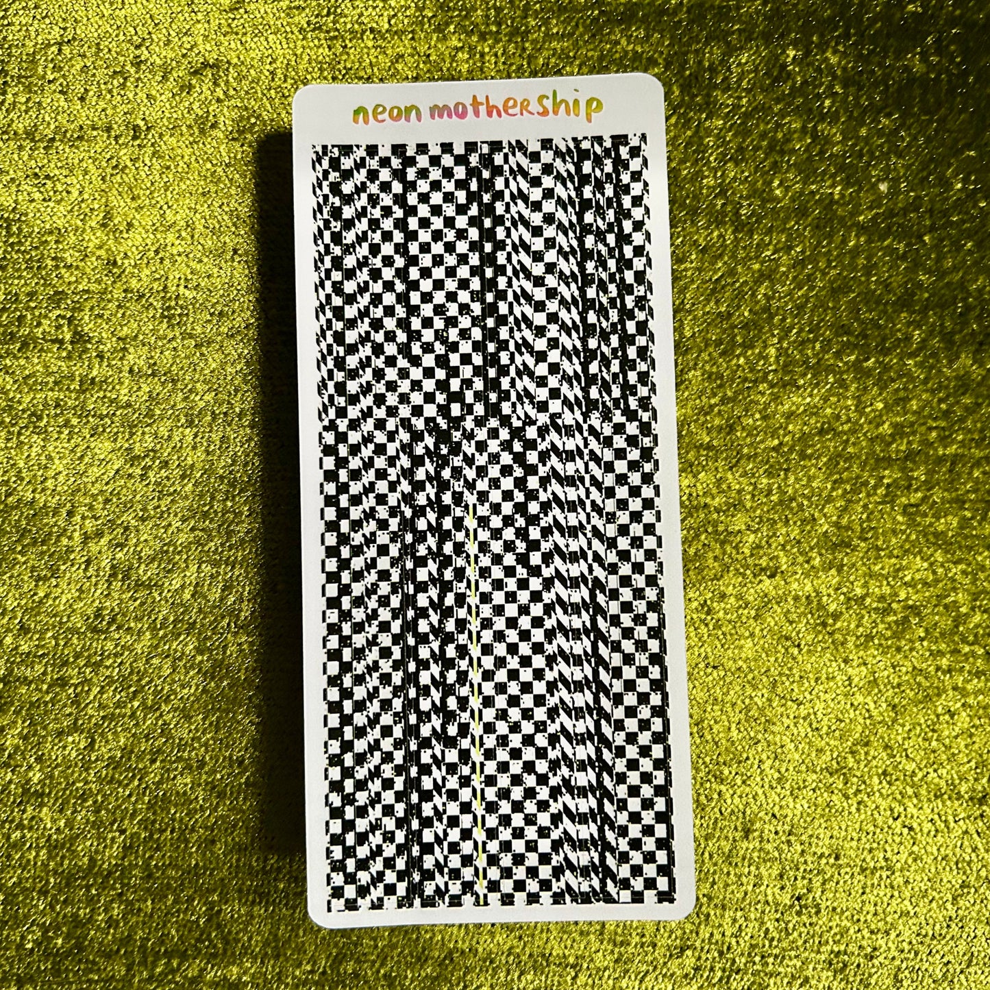 Sticker sheet with a black and white checkered pattern on a textured green surface
