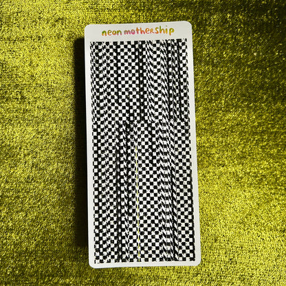 Sticker sheet with a black and white checkered pattern on a textured green surface