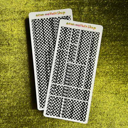 Two checkered sticker sheets with 'neon mothership' branding on a green textured surface