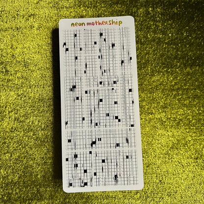 Sticker sheet with grid pattern and 'neon motherShip' text on a green textured surface