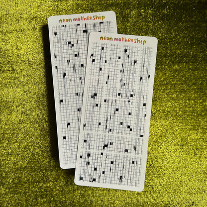 Two grid sticker sheets with text on a green textured surface