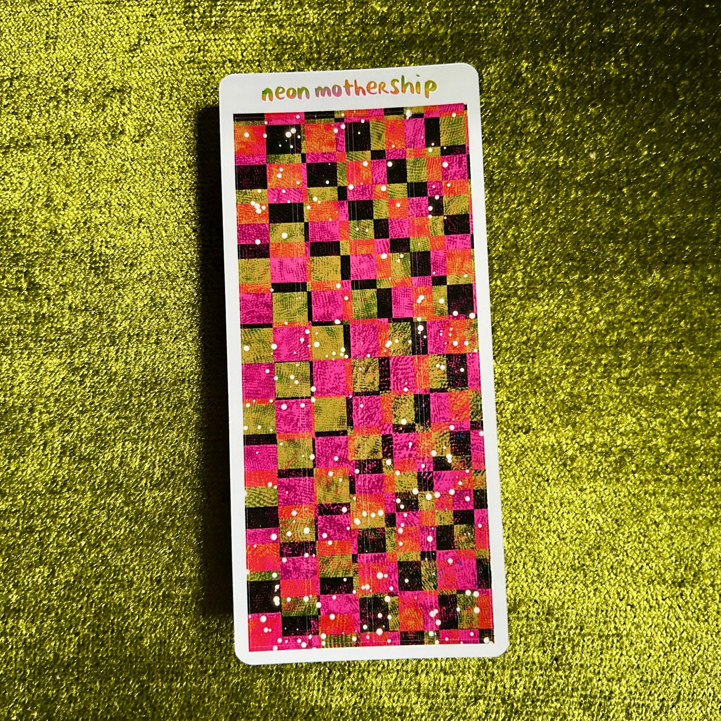 Sticker with a checkered pattern on a green textured surface